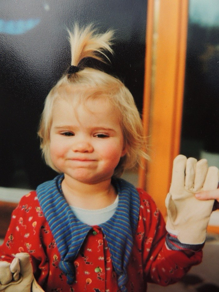 Carolin as a toddler wearing oversized work gloves